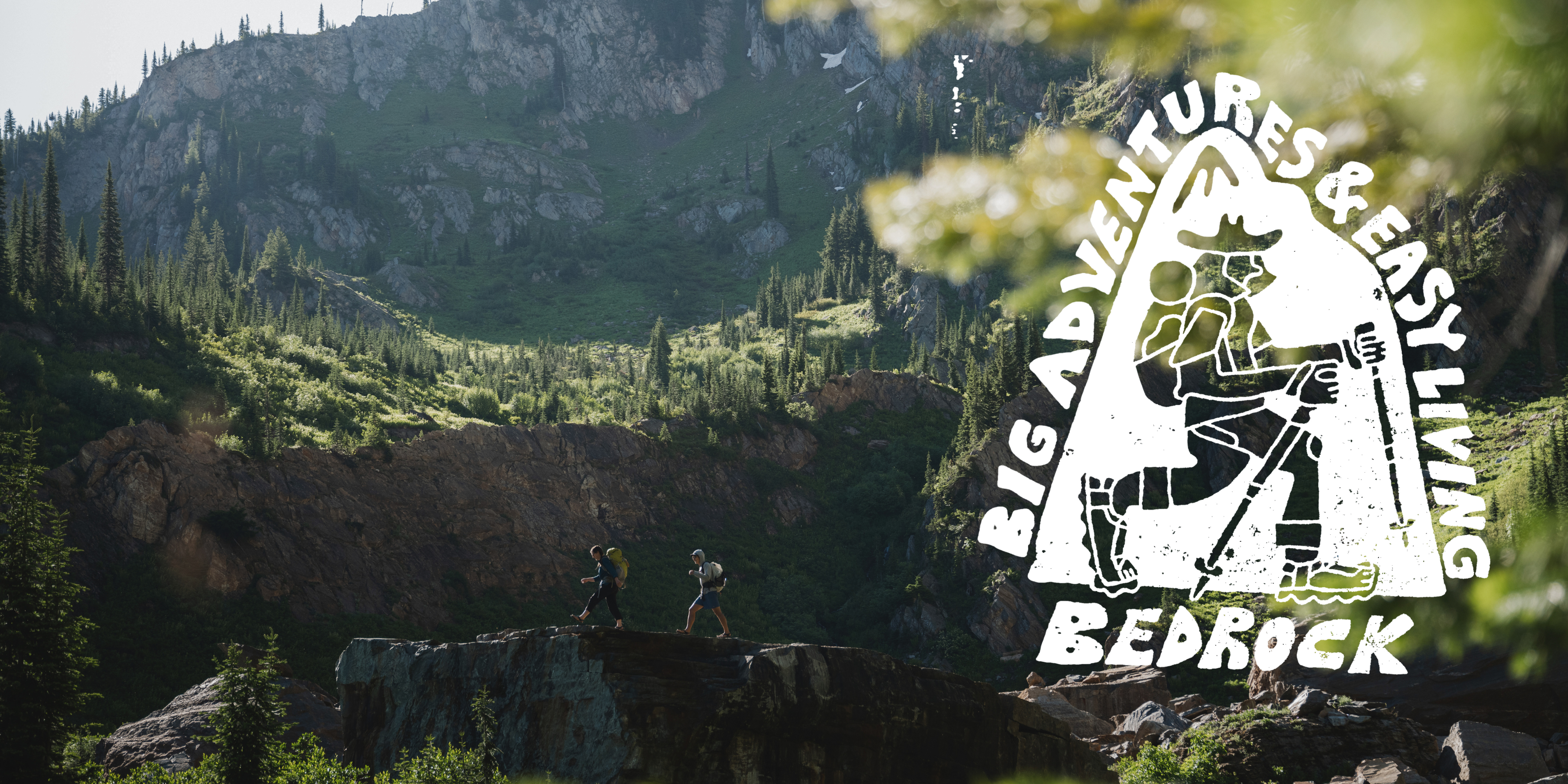 A mountainous  and green landscape with two people trekking in the foreground. There is a large illustration of a hiker with the message 'Big Adventures & Easy Living Bedrock'.